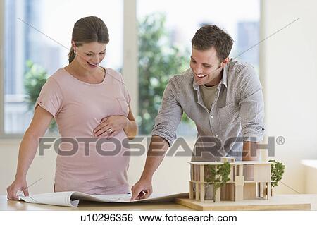 Stock Photograph - Young couple looking at blueprints. Fotosearch
