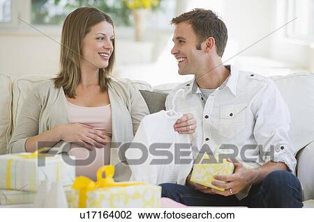 Stock Image - Young couple opening gifts for baby. Fotosearch