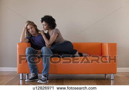 Young couple sitting on sofa View Large Photo Image Stock Image - Young couple sitting on sofa. Fotosearch