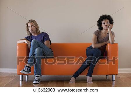 Young couple sitting on sofa View Large Photo Image Stock Image - Young couple sitting on sofa. Fotosearch