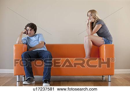 Young couple sitting on sofa View Large Photo Image Stock Image - Young couple sitting on sofa. Fotosearch
