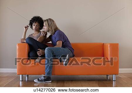 Stock Photograph - Young couple sitting on sofa. Fotosearch