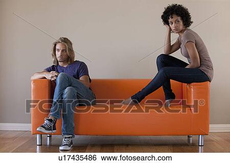 Young couple sitting on sofa View Large Photo Image Stock Photograph - Young couple sitting on sofa. Fotosearch