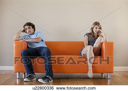 Stock Photograph - Young couple sitting on sofa. Fotosearch