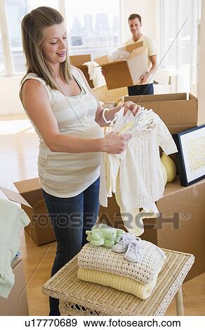 Young couple unpacking baby clothing View Large Photo Image Stock Photo - Young couple unpacking baby clothing. Fotosearch