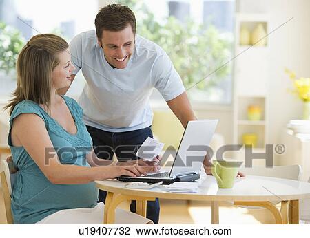 Stock Image - Young couple using laptop. Fotosearch