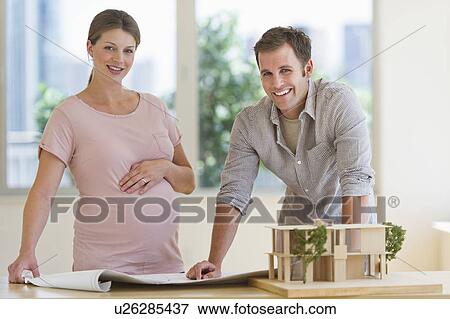 Young couple with blueprints and house model View Large Photo Image Stock Photo - Young couple with blueprints and house model. Fotosearch