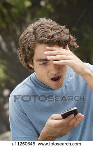 Young man reading sms View Large Photo Image Stock Photograph - Young man reading sms. Fotosearch