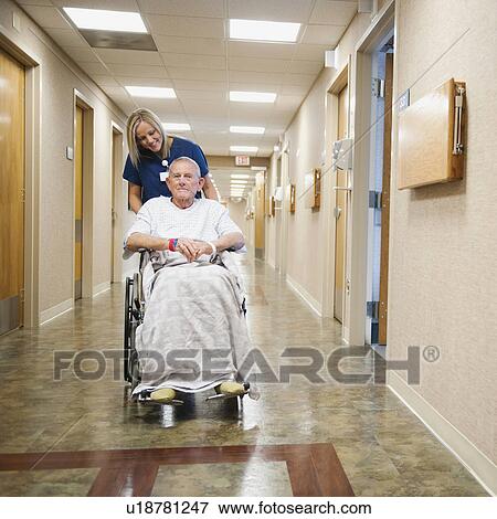 Stock Photo - Young nurse is pushing senior man in wheelchair. Fotosearch