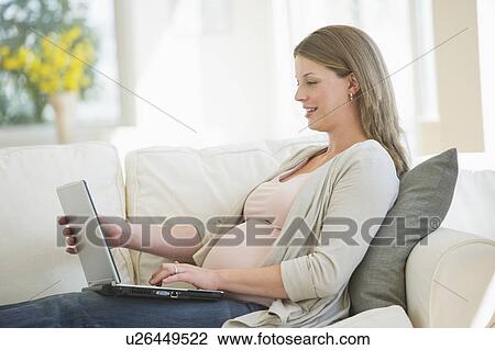 Stock Image - Young pregnant woman doing using laptop. Fotosearch