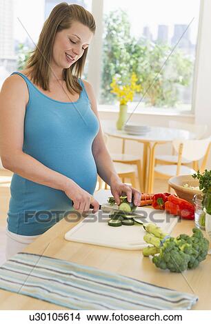 Young pregnant woman preparing food View Large Photo Image Picture - Young pregnant woman preparing food. Fotosearch