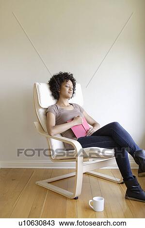 Stock Image - Young woman napping in armchair. Fotosearch