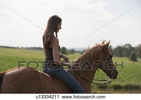 Stock Image - Young woman riding horse. Fotosearch