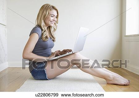 Young woman sitting in room using laptop View Large Photo Image Stock Photo - Young woman sitting in room using laptop. Fotosearch