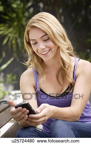 Young woman text-messaging in park View Large Photo Image Stock Image - Young woman text-messaging in park. Fotosearch
