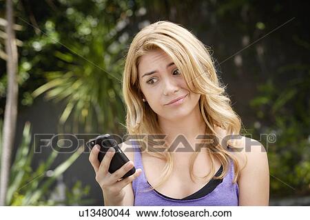 Picture - Young woman text-messaging, with facial expression. Fotosearch