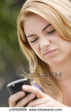 Stock Photograph - Young woman text-messaging, with facial expression. Fotosearch