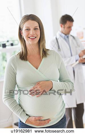 Stock Image - Young woman with doctor in doctor's office. Fotosearch