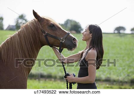 Stock Image - Young woman with horse in field. Fotosearch