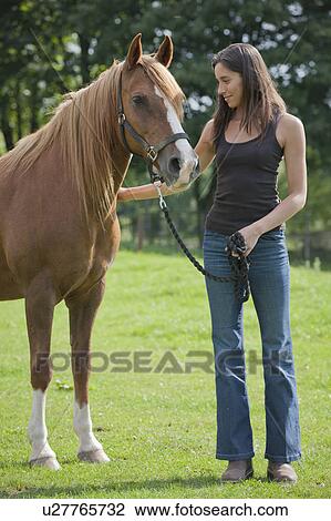 Stock Image - Young woman with horse in field. Fotosearch