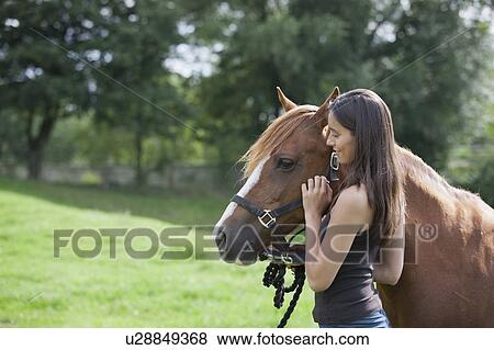 Stock Photo - Young woman with horse in field. Fotosearch