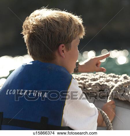 Picture - Boy sitting in a panga boat and pointing, Tagus Cove, Isabela Island, Galapagos Islands, Ecuador. Fotosearch