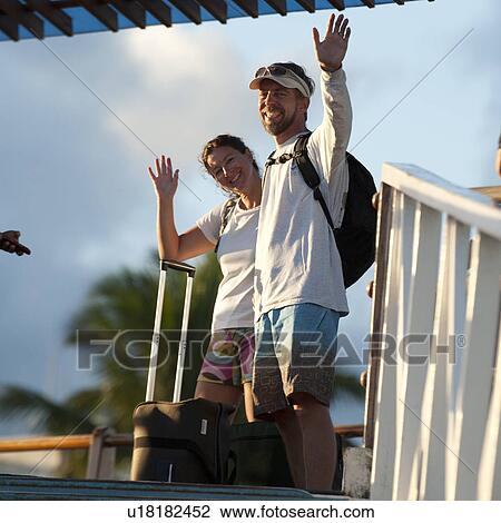 Stock Image - Couple waving their hand and smiling, Puerto Ayora, Santa Cruz Island, Galapagos Islands, Ecuador. Fotosearch
