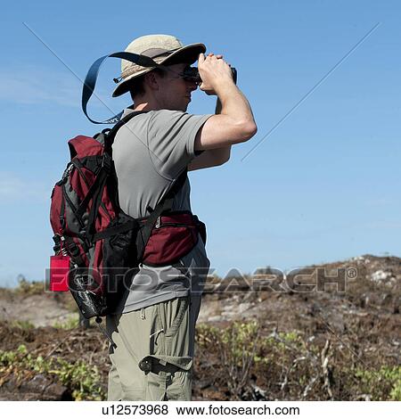 Stock Photo - Man looking through a binoculars, Prince Philip's Steps, Tower Island, Darwin Bay, Genovesa Island, Galapagos Islands, Ecuador. Fotosearch