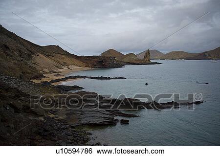 Stock Photograph - Rocky coast with Pinnacle Rock in the background, Bartolome island, Galapagos Islands, Ecuador. Fotosearch