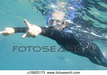 Stock Image - Scuba diver swimming underwater, Puerto Egas, Santiago Island, Galapagos Islands, Ecuador. Fotosearch