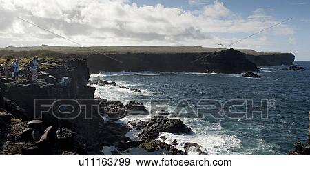 Stock Photo - Tourists at a rocky coast, Punta Suarez, Espanola Island, Galapagos Islands, Ecuador. Fotosearch