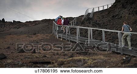 Stock Photography - Tourists walking on a stepped walkway on a volcanic landscape, Bartolome island, Galapagos Islands, Ecuador. Fotosearch
