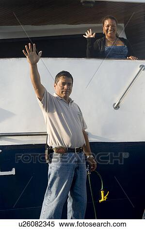Stock Photography - Tourists waving hands from a boat, Puerto Baquerizo Moreno, San Cristobal Island, Galapagos Islands, Ecuador. Fotosearch