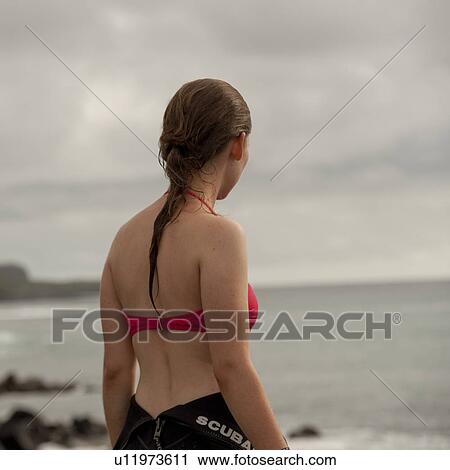 Stock Image - Woman on the coast looking at a view, Playa Ochoa, San Cristobal Island, Galapagos Islands, Ecuador. Fotosearch