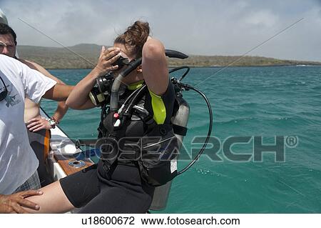 Stock Image - Woman preparing for scuba diving, San Cristobal Island, Galapagos Islands, Ecuador. Fotosearch