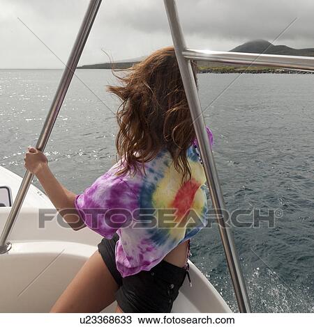 Stock Image - Woman sitting in a boat looking at a view, San Cristobal Island, Galapagos Islands, Ecuador. Fotosearch