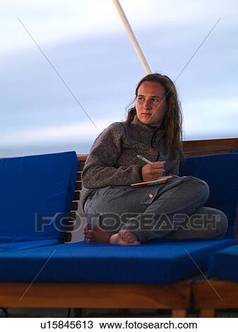 Stock Image - Woman sitting on a boat and writing, Galapagos Islands, Ecuador. Fotosearch