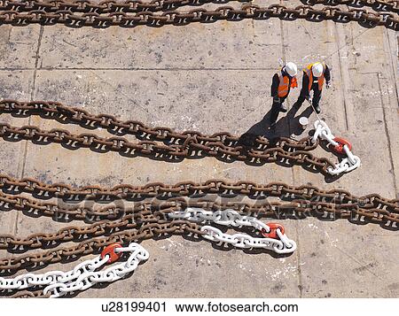 Stock Image - Aerial view of workers examining chain. Fotosearch