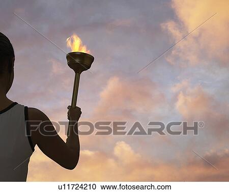 Stock Image - Athlete holding flaming baton. Fotosearch