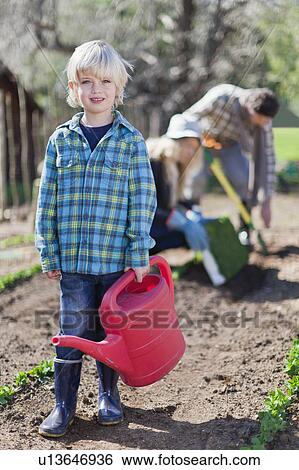 Boy carrying watering can in garden View Large Photo Image Stock Photograph - Boy carrying watering can in garden. Fotosearch