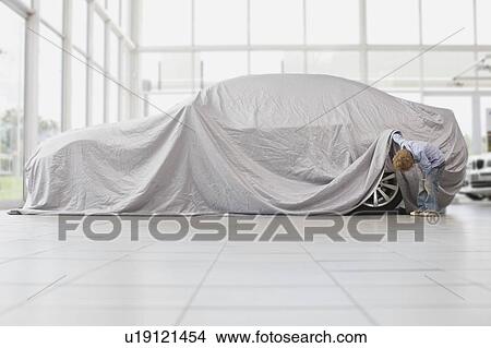 Picture - Boy peeking under cloth on car. Fotosearch