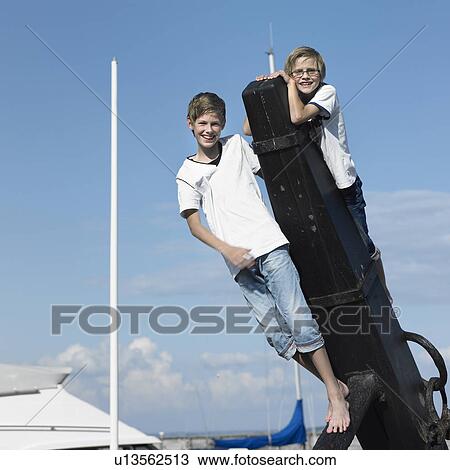 Stock Image - Boys climbing on pier. Fotosearch