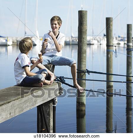 Stock Photograph - Boys eating ice cream on pier. Fotosearch