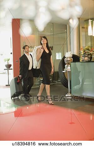 Stock Photograph - Business people rolling luggage in hotel. Fotosearch