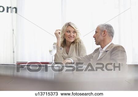 Stock Image - Business people talking in lobby area. Fotosearch