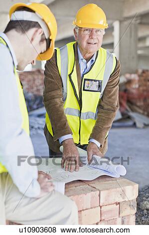 Stock Photo - Businessman and worker with blueprints. Fotosearch