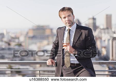 Businessman having a drink on rooftop View Large Photo Image Stock Image - Businessman having a drink on rooftop. Fotosearch