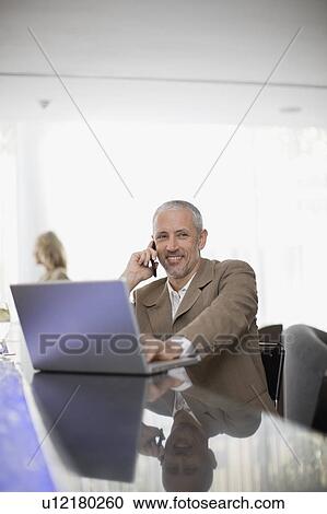Businessman on phone using laptop View Large Photo Image Stock Image - Businessman on phone using laptop. Fotosearch