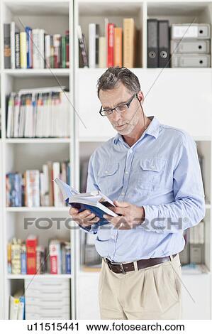 Businessman reading book in office View Large Photo Image Stock Image - Businessman reading book in office. Fotosearch