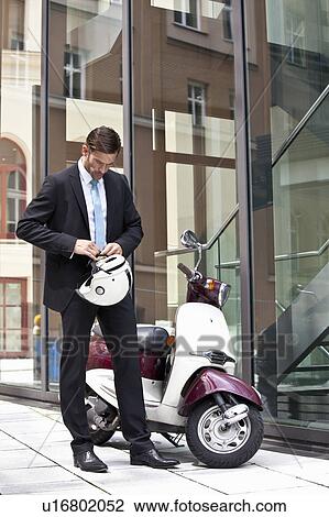 Businessman tying helmet to scooter View Large Photo Image Stock Image - Businessman tying helmet to scooter. Fotosearch